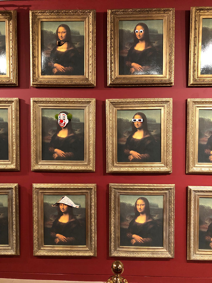 A wall of Mona Lisa copies with art & squiggles across her face.